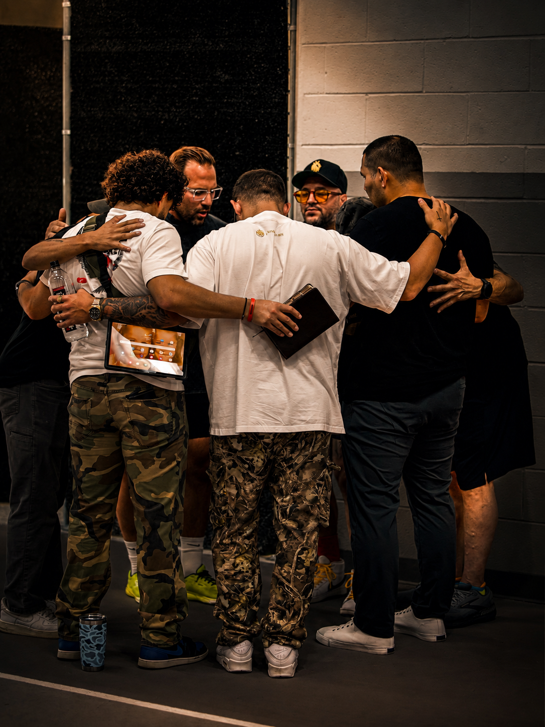 Men praying together in a huddle at a Kingdom Minded Man gathering